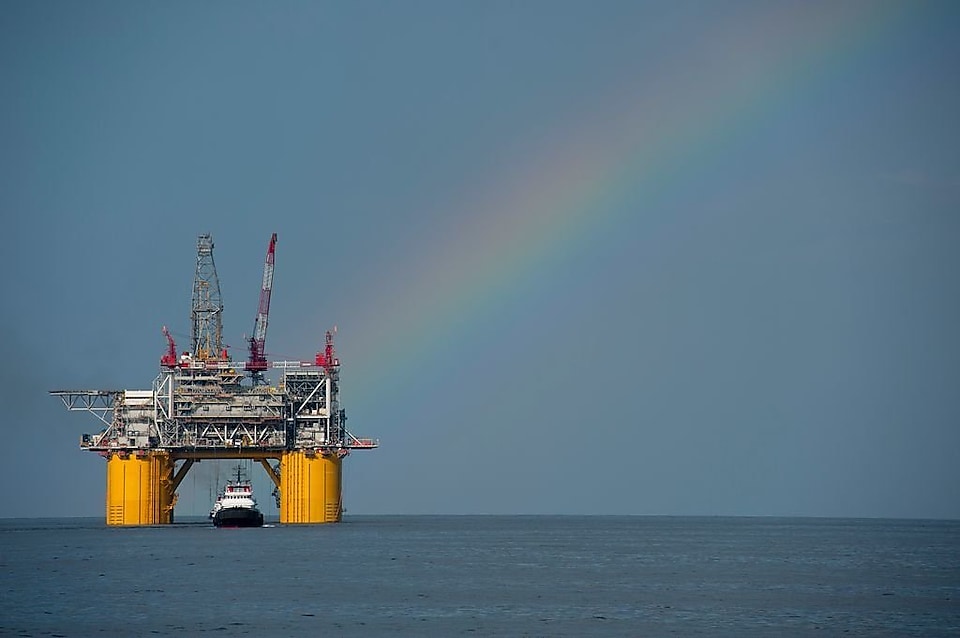 A Shell offshore rig with a rainbow in the background.