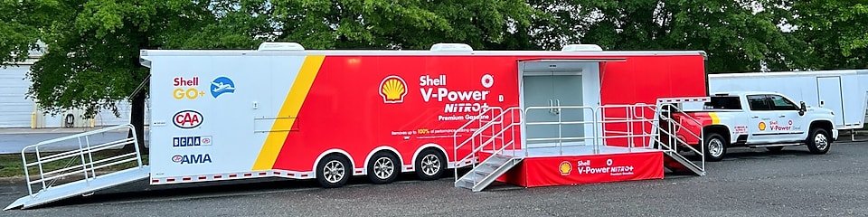 The roof of a Shell Station with white, red and yellow on it there is blue sky in the background. 